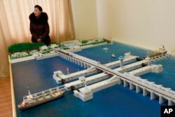 A guide stands next to a model of the West Sea Barrage in Nampo, North Korea, Feb. 2, 2019. North Korea is exploring alternative energy sources.