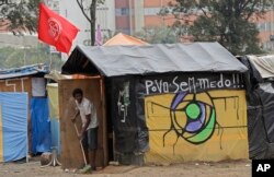 In this Tuesday, Dec. 12, 2017 photo, bricklayer Luciano Oliveira sweeps outside his shack in the squatter community coined "Povo Sem Medo," or Fearless People, in Sao Bernardo do Campo,