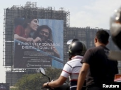 FILE - Motorists ride past a billboard displaying Facebook's Free Basics initiative in Mumbai, India.