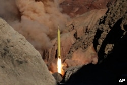 FILE - In this photo obtained from the Iranian Fars News Agency, a Qadr H long-range ballistic surface-to-surface missile is fired by Iran's Revolutionary Guard, during a maneuver, in an undisclosed location in Iran, March 9, 2016.