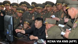 North Korean leader Kim Jong Un, center, looks at a computer as he inspects a shelling drill of a long-range artillery.