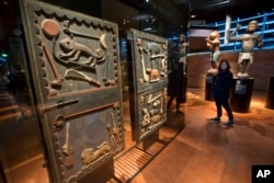 A visitor walks past a door of the king's palace Gele of the Dahomey kingdom, dated19th century, today's Benin, at Quai Branly museum in Paris, Nov. 23, 2018.