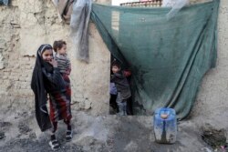 Seorang anak laki-laki pengungsi mengintip dari hunian sementara di Kota Kabul, Afghanistan, 30 Desember 2020.