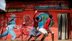 Children run down a street past an informational mural warning people about the dangers of coronavirus in the Kibera slum of Nairobi, Kenya on Wednesday, June 3, 2020.