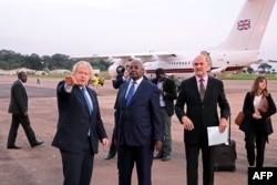 Ugandan Minister of Foreign Affairs Sam Kahamba Kutesa (C) welcomes British Foreign Secretary Boris Johnson (L), next to British High Commissioner to Uganda Peter West (R), upon his arrival at the Entebbe International Airport on March 15, 2017.