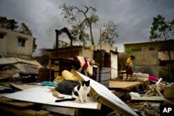 Efrain Diaz Figueroa, right, walks by his sister's home destroyed in the passing of Hurricane Maria, in San Juan, Puerto Rico, Oct. 9, 2017.