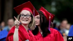 Dunellen High School senior Destiny Lightfoot, points to a sign in the crowd after receiving her diploma during graduation ceremonies Wednesday, June 21, 2017, in Dunellen, N.J. (AP Photo/Julie Jacobson)