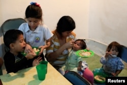 The children of Viviana Colmenares (C) have lunch in a community diner at the slum of Petare in Caracas, Feb. 22, 2018.