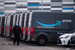 Seorang karyawan Amazon berjalan di dekat barisan truk layan antar Amazon Prime i Brandizzo, dekat Turin, 22 Maret 2021.