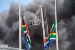 Firemen spray water on flames erupting from a building at South Africa's Parliament in Cape Town Sunday Jan. 2, 2022.