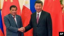 FILE - Philippine President Rodrigo Duterte, left, and Chinese President Xi Jinping pose for photographers on the sidelines of the Belt and Road Forum for International Cooperation at the Great Hall of the People in Beijing, May 15, 2017.