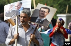 A Syrian man holds portraits of President Bashar al-Assad, right, and Russian President Valdimir Putin, left, as several hundred people gathered near the Russian Embassy in Damascus to express their support for Moscow's air war in Syria.