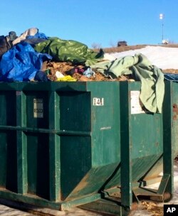 Trash waits to be hauled away at the Dakota Access oil pipeline protest camp as a National Guard Humvee monitors the camp from a nearby hilltop, Feb. 16, 2017.