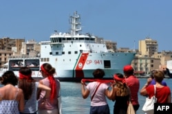 Members of a red T-shirt movement look on as Italy's Diciotti coast guard vessel, carrying 67 asylum seekers, waits in Trapani port, July 12, 2018.