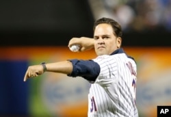 FILE - Retired New York Mets catcher Mike Piazza winds up before throwing out the ceremonial first pitch in a baseball game between the Mets and the New York Yankees in New York, Sept. 20, 2015.