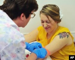A nurse draws blood from Heidi Wyandt, March 29, 2017. Wyandt is helping test an experimental non-opioid pain medication. With about 2 million Americans hooked on opioid painkillers, researchers and drug companies are searching for less addictive drugs.