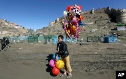 FILE - A young boy sells balloons in Kabul, March 23, 2017. Aid group Save the Children said earlier this year that nearly a third of all children in war-torn Afghanistan are unable to attend school, leaving them at increased risk of child labor, recruitment by armed groups, early marriage and other forms of exploitation.