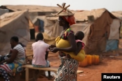 FILE - A woman carries her child in a camp sheltering internally displaced people next to the M'Poko international airport, February 13, 2016.