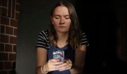 In this Monday, July 22, 2019 photo, Rachel Whalen looks at her phone at her home in Draper, Utah. Whalen remembers feeling gutted in high school when a former friend would mock her online postings, threaten to unfollow or unfriend her on social media and