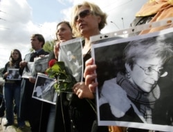 FILE - Ukrainian women hold flowers and portraits during a ceremony to commemorate murdered journalist Anna Politkovskaya, in front of the Russian embassy in Kyiv, Oct. 10, 2006.
