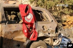 This image provided by the Syrian anti-government group Aleppo 24 news, shows a vest of the Syrian Arab Red Crescent hanging on a damaged vehicle, in Aleppo, Syria, Sept. 20, 2016.