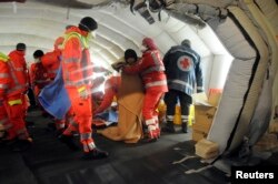 Medics help migrants in a tent after they arrived onboard the Blue Sky M cargo ship at the Gallipoli harbor, southern Italy, Dec. 31, 2014.