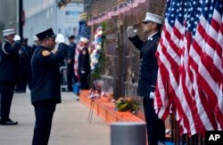 FIRE - New York City firefighters salute in front of a memorial on the side of a firehouse adjacent to One World Trade Center and the 9/11 Memorial site during ceremonies on the anniversary of the 9/11 terrorist attacks in New York, Sept. 11, 2018.
