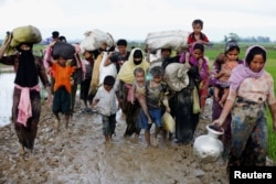 Pengungsi Rohingya melewati jalanan berlumpur setelah melewati perbatasan Bangladesh-Myanmar di Teknaf, Bangladesh, 1 September 2017.