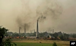 FILE - Smoke rises from chimneys of brick kilns on the outskirts of New Delhi, India, June 16, 2015.