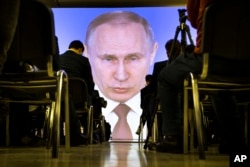 FILE - Journalists watch as Russian President Vladimir Putin gives his annual state of the nation address in Manezh in Moscow, March 1, 2018.