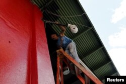 Cuban migrant Barbaro Rodriguez, 43, who ran out of money, works painting a private business in Paso Canoas, Panama, March 22, 2016. "I am presently earning $20 a day painting this building. Hopefully, I can make enough money to continue our journey" to the U.S., he says.