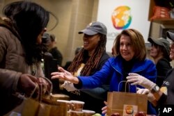 House Speaker Nancy Pelosi of California, center, helps give out food at World Central Kitchen, the not-for-profit organization started by Chef Jose Andres, Jan. 22, 2019, in Washington.