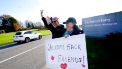 FILE - Dual U.S.-Canadian citizen Traysi Spring, right, and her American husband Tom Bakken, hold a homemade sign to welcome people heading into the U.S. from Canada, Nov. 8, 2021, in Blaine, Wash. The U.S. reopened its land borders to nonessential travel at that time after almost 20 months of COVID-19 restrictions. Now the U.S. has again discouraged travel to the north.
