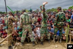 Bangladeshi soldiers stand guard as Rohingya Muslims, who crossed over from Myanmar into Bangladesh, wait to receive aid at a refugee camp near Balukhali, Sept. 28, 2017.