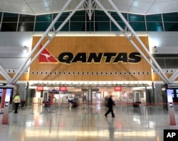 FILE - Two security workers walk through a near empty Qantas domestic terminal at Sydney Airport in Sydney, Oct. 29, 2011.