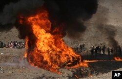 FILE - Afghan security personnel watch as flames and smoke rise after opium and narcotics are burned in a ceremony in Kabul, Afghanistan, Dec. 20, 2016.
