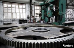 FILE - A man works on a production line for manufacturing units for ski lifts, at a machinery company in Zhangjiakou, Hebei province, China, Aug. 6, 2018.