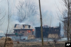 Flames and smoke billows from residential buildings where militants are suspected to have taken refuge during a gun battle in Pulwama, south of Srinagar, Indian controlled Kashmir, Feb. 18, 2019.