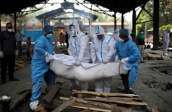 Petugas kesehatan dan kerabat yang mengenakan alat pelindung diri (APD) membawa jenazah seorang pria yang meninggal karena COVID-19, di krematorium di New Delhi, India, 21 April 2021. (Foto: Reuters/Adnan Abidi)