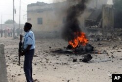 Policier somalien debout près d'une voiture détruite dans une explosion à Mogadiscio, le 6 décembre 2011