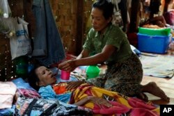 FILE - A family member takes care of a patient at an HIV/AIDS care center in the outskirts of Yangon, Myanmar, March 1, 2014.