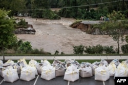 Floodwaters rush through the breach of the Columbia Canal as emergency workers prepare giant sandbags to plug the hole in Columbia, S.C., Oct. 5, 2015.