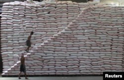 FILE - A worker walks up a pile of rice at a warehouse of the Philippines National Food Authority in Manila, May 12, 2015.