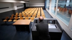 Seorang profesor mengajar di ruangan yang kosong, sementara mahasiswanya mengikuti kuliahnya online selama pandemi corona.