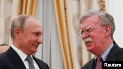 Russia -- Russian President Vladimir Putin (L) shakes hands with U.S. National Security Adviser John Bolton