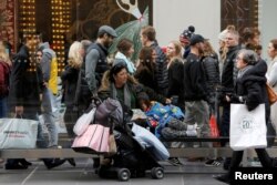 A woman sits at a bus stop with a child during Black Friday in Manhattan, New York, Nov. 25, 2016.
