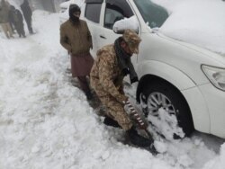Seorang tentara membersihkan salju di bawah kendaraan yang terdampar setelah hujan salju lebat di Murree, Pakistan 8 Januari 2022. (Foto: Inter Services Public Relations/ISPR via REUTERS)