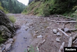 FILE - Wood debris from logging operations upstream can be seen in a valley in Arges county, north of Bucharest, Romania, Aug. 19, 2016.