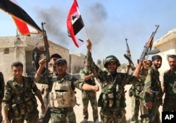 FILE - Syrian soldiers celebrate the capture of Achan, Hama province, Syria, Oct. 11, 2015.