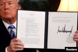U.S. President Donald Trump holds up a proclamation declaring his intention to withdraw from the JCPOA Iran nuclear agreement after signing it in the Diplomatic Room at the White House in Washington, May 8, 2018.